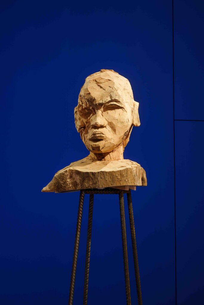 Kader Attia. Nimetön (Janus), 2020/2026, puu, 80 x 50 x 90 cm, teräsjalusta 160 x 50 x 50 cm. Kuva: Hanna Wiedemann / HKW.